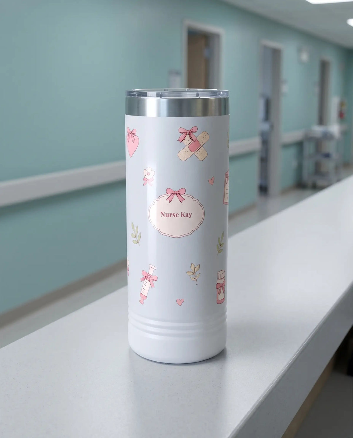 Bow Toss, Nurse wrap on a white 22oz Skinny tumbler personalized Nurse Kay, a clean hospital nurses' station counter