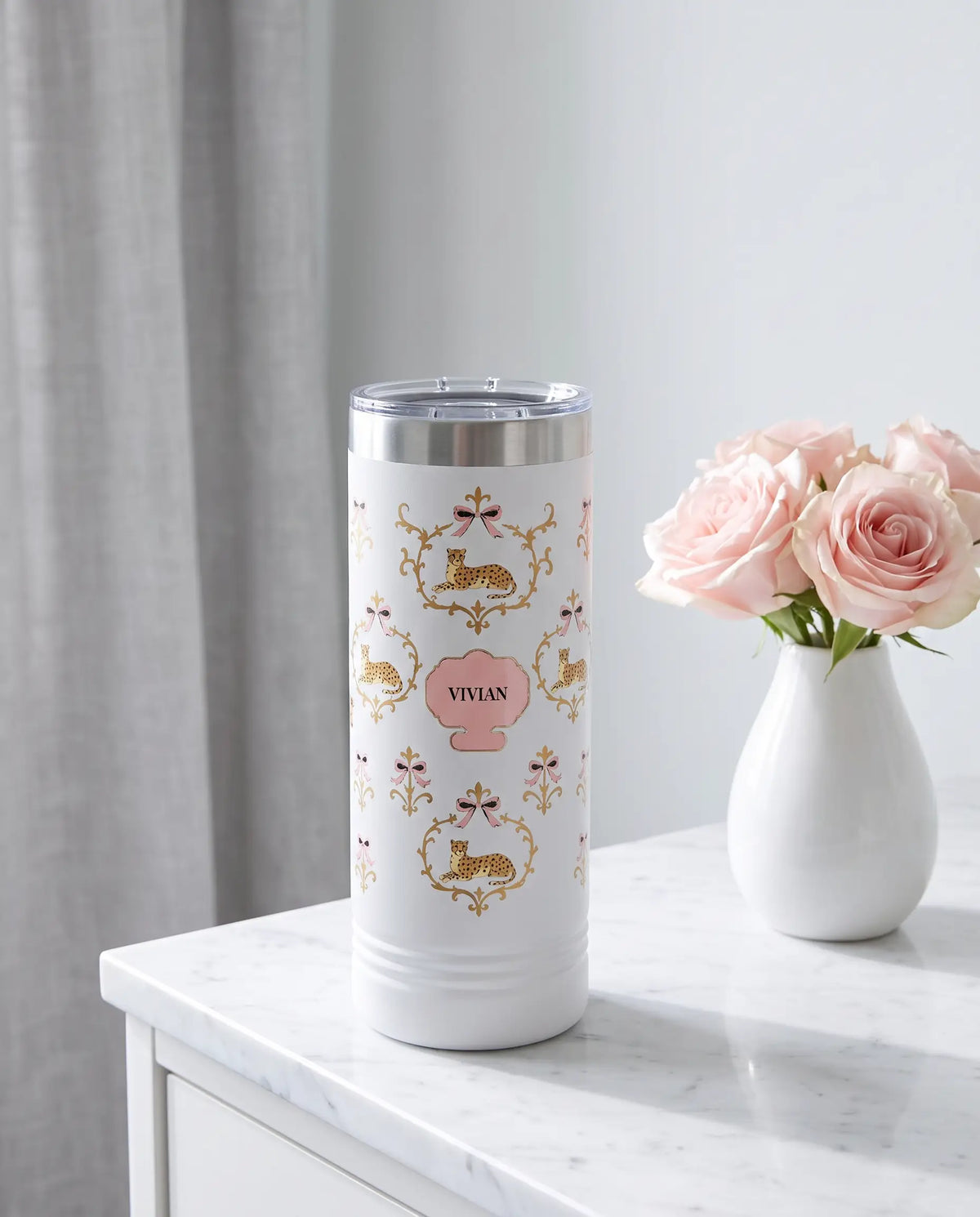 Cheetah Damask wrap on a white 22oz Skinny tumbler personalized VIVIAN, a marble vanity top in a softly lit dressing room