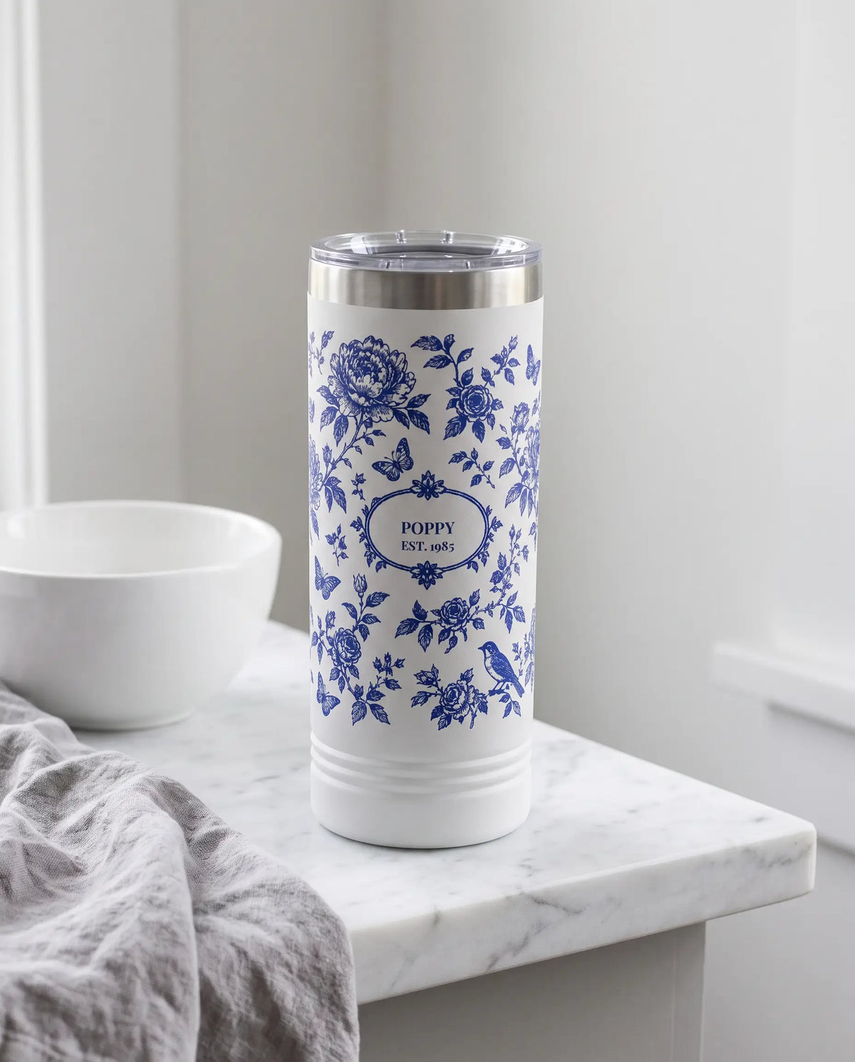 Botanical Toile wrap on a white 22oz Skinny tumbler personalized POPPY, EST. 1985, a farmhouse kitchen counter of white marble