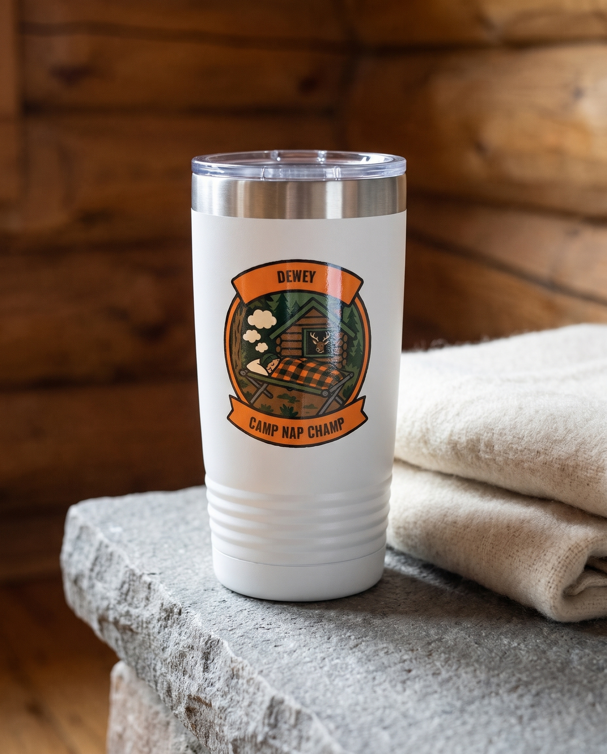 Deer Camp Patch, Camp Nap Champ badge on a white 20oz tumbler personalized DEWEY, CAMP NAP CHAMP, a stone hearth ledge in a log cabin