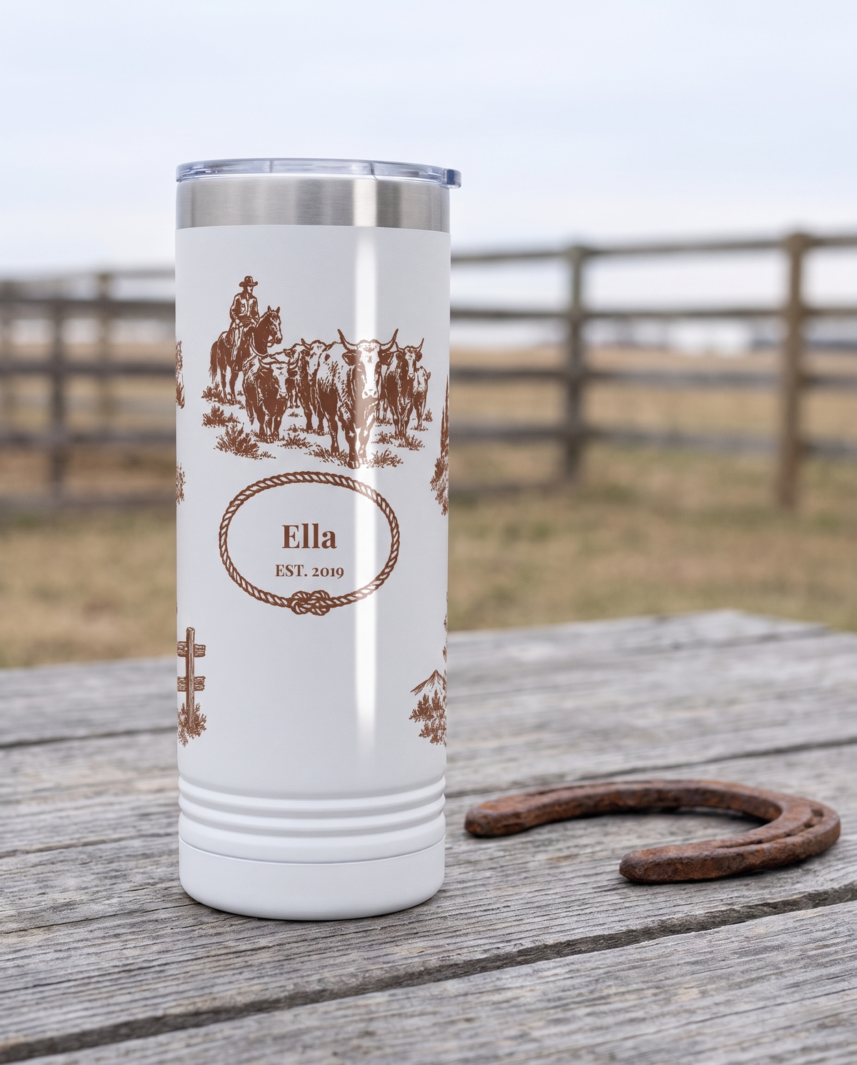 Western Toile, Pony and Chapel wrap on a white 22oz Skinny tumbler personalized ELLA, EST. 2019, a weathered barnwood table on a ranch porch