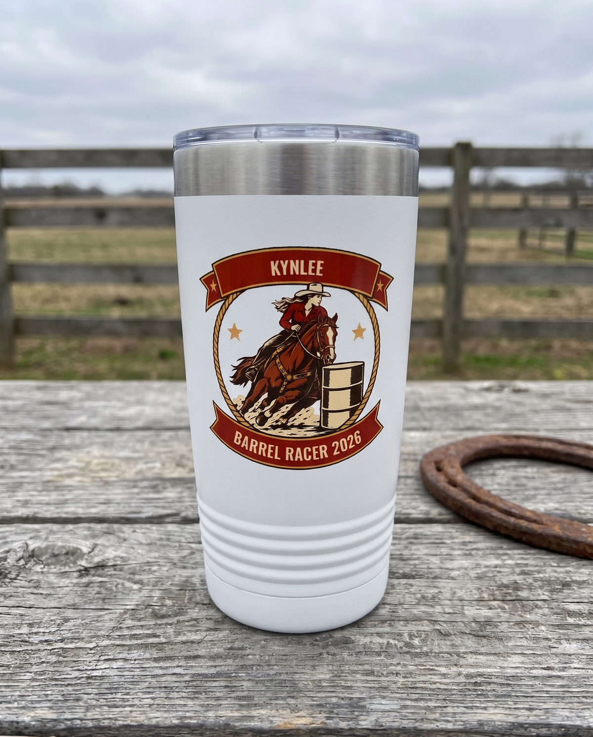 Rodeo Program, Barrel Racer badge on a white 20oz tumbler personalized KYNLEE, BARREL RACER 2026, a weathered barnwood table on a ranch porch