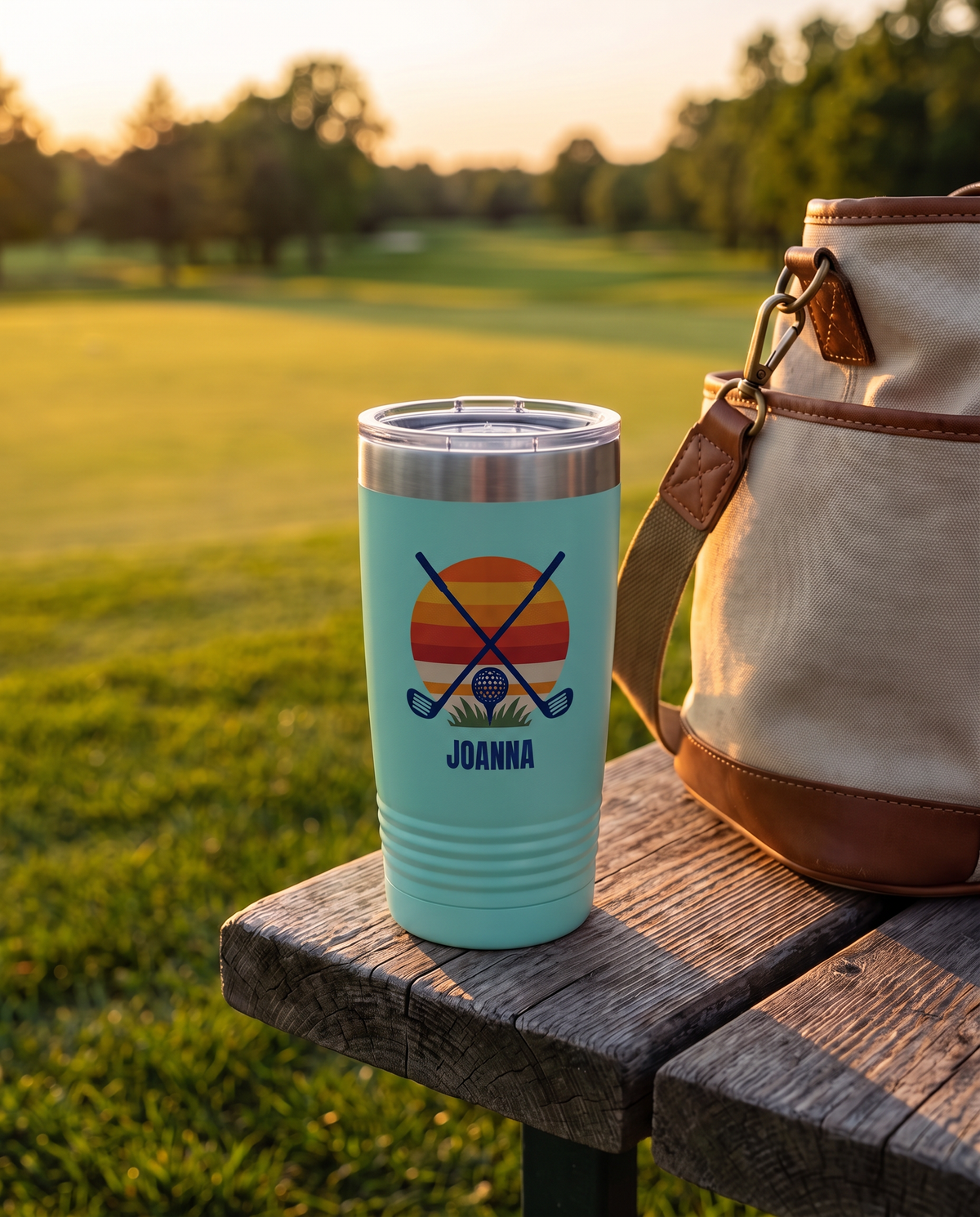 Retro Sunset Clubs personalized golf tumbler on a tee box bench at golden hour, name JOANNA