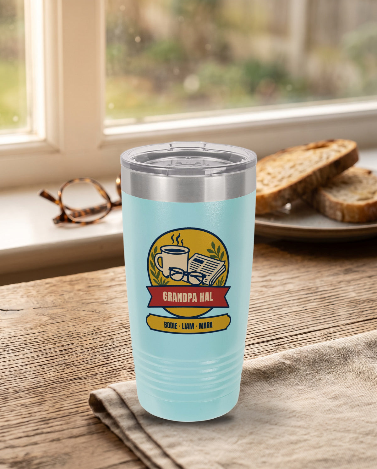 Morning Paper Badge, a morning coffee badge in gold, cream, red, navy and olive, UV printed on the front of a 20oz Ringneck tumbler in Light Blue, sample name GRANDPA HAL