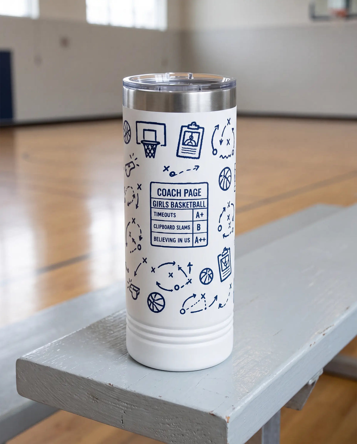 Coach Chalk Talk, Basketball wrap on a white 22oz Skinny tumbler personalized COACH PAGE, GIRLS BASKETBALL, the pale gray bleacher bench of a school gym