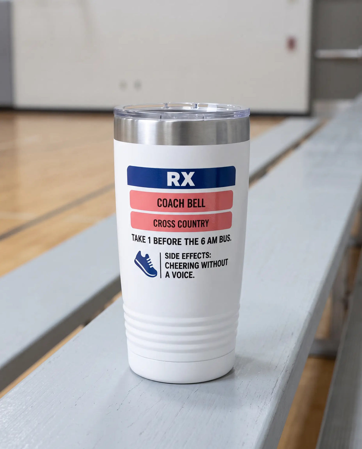 Rx Label, Coach badge on a white 20oz tumbler personalized COACH BELL, CROSS COUNTRY, the pale gray bleacher bench of a school gym