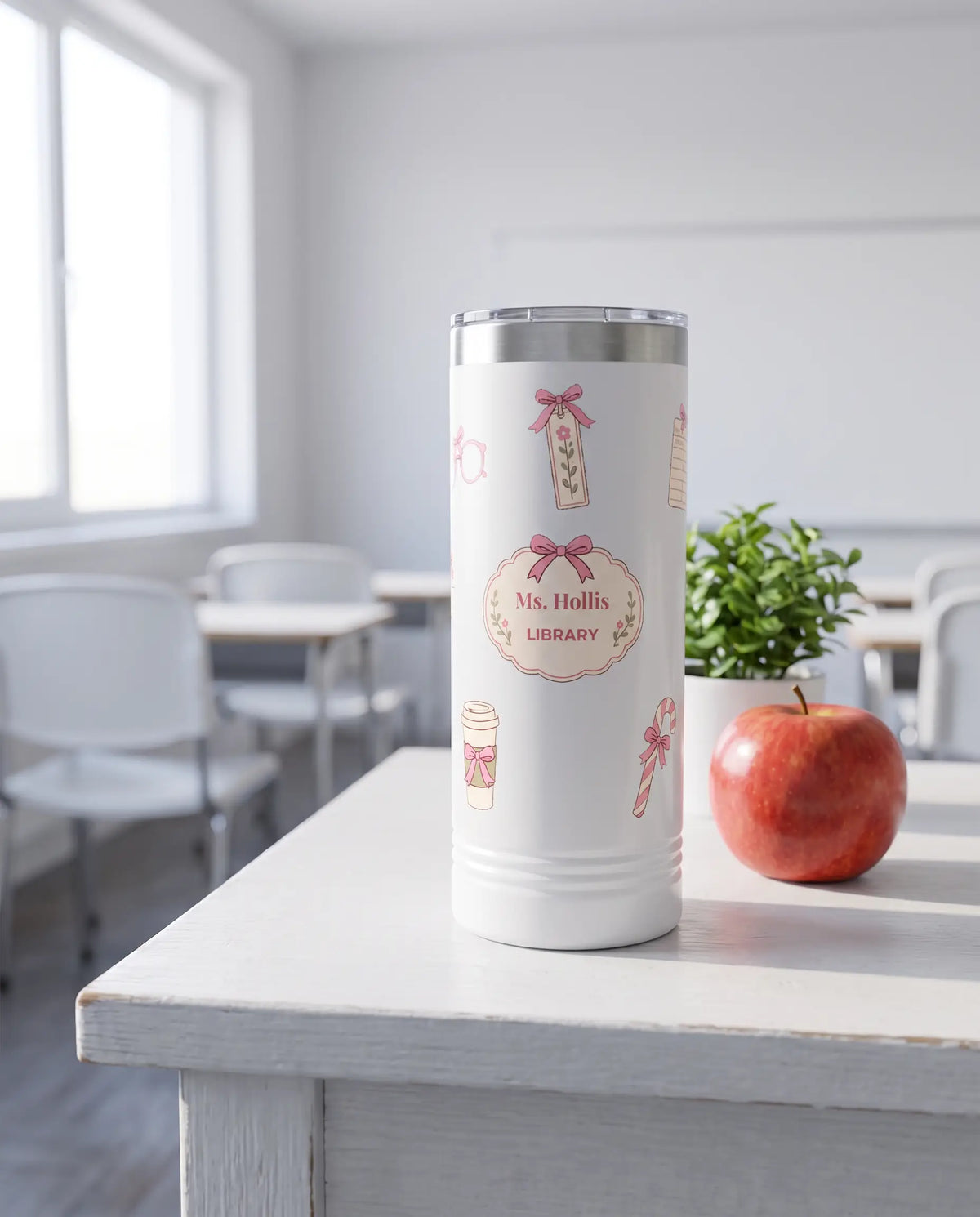 Bow Toss, Librarian wrap on a white 22oz Skinny tumbler personalized Ms. Hollis, LIBRARY, a white-painted teacher's desk by a sunny classroom window