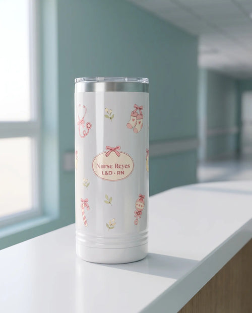 Bow Toss, L&D Nurse wrap on a white 22oz Skinny tumbler personalized Nurse Reyes, L&D - RN, a clean hospital nurses' station counter