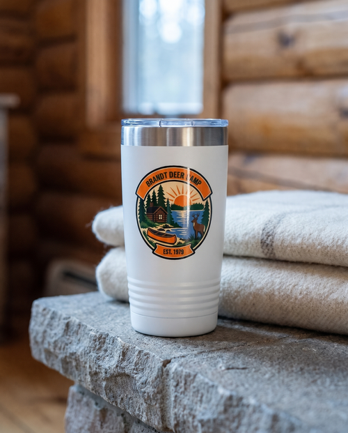 Deer Camp Patch, Lake Cabin badge on a white 20oz tumbler personalized BRANDT DEER CAMP, EST. 1979, a stone hearth ledge in a log cabin