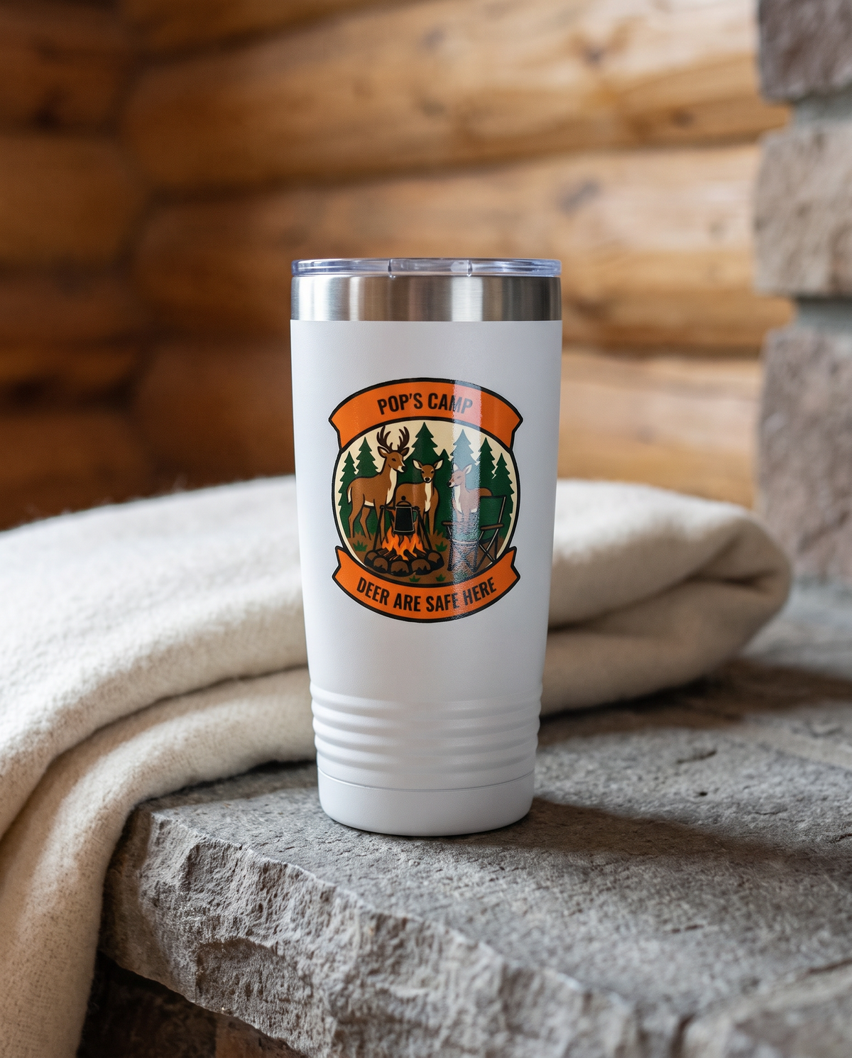 Deer Camp Patch, Deer Are Safe Here badge on a white 20oz tumbler personalized POP'S CAMP, DEER ARE SAFE HERE, a stone hearth ledge in a log cabin