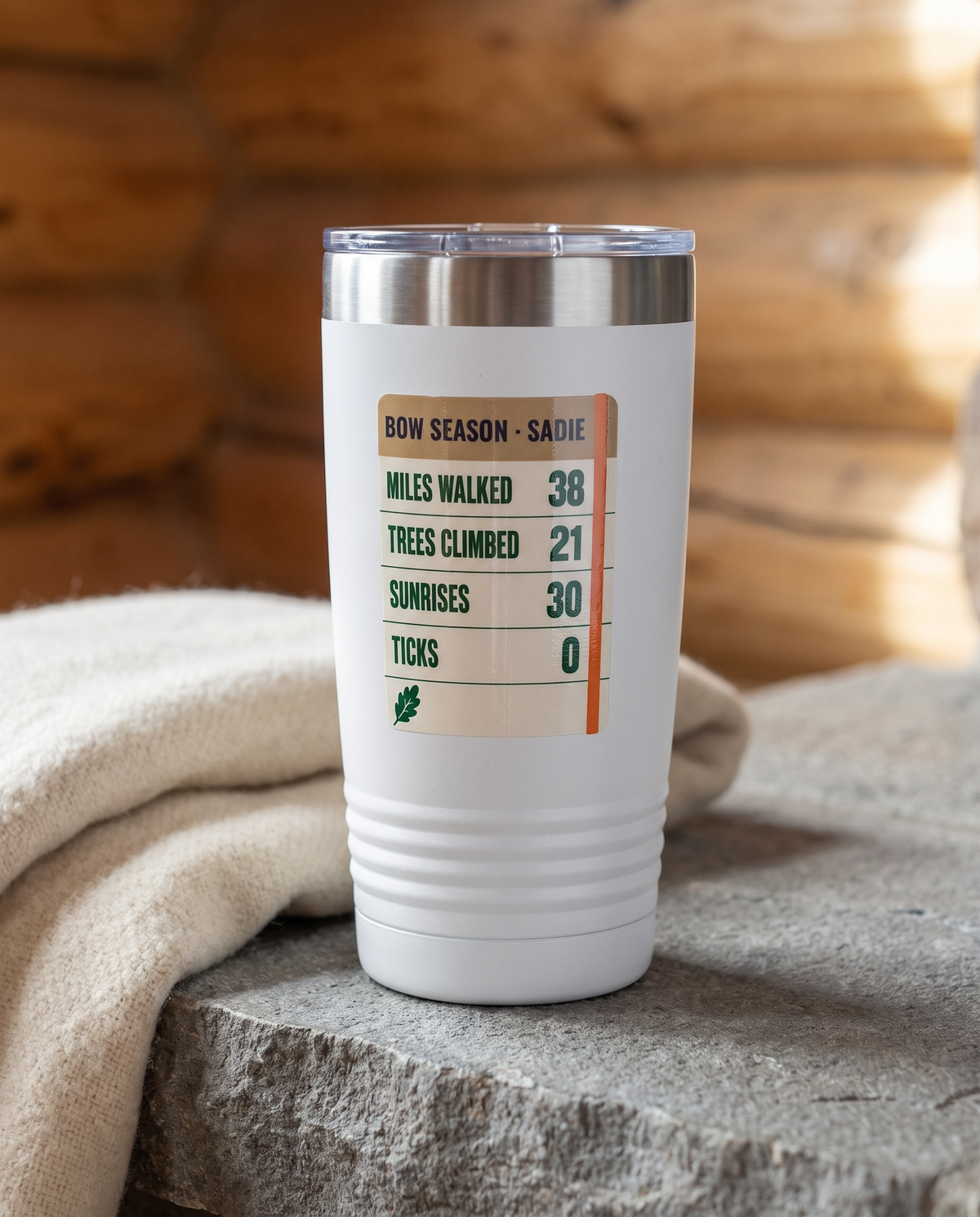 Season Log, Bow Season badge on a white 20oz tumbler personalized BOW SEASON - SADIE, a stone hearth ledge in a log cabin