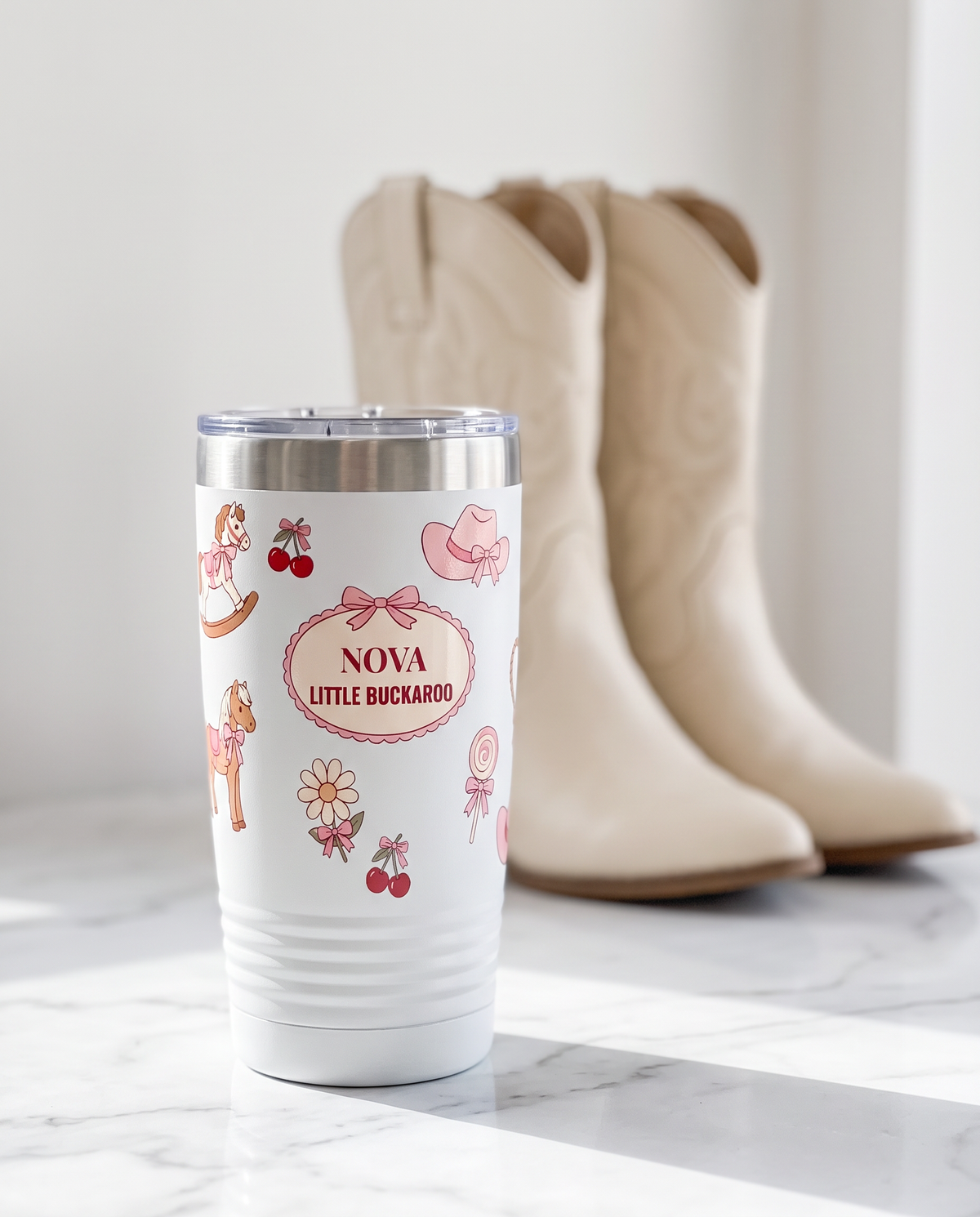 Coquette Cowgirl, Little Buckaroo wrap on a white 20oz tumbler personalized NOVA, LITTLE BUCKAROO, a white marble vanity top in a bright boutique