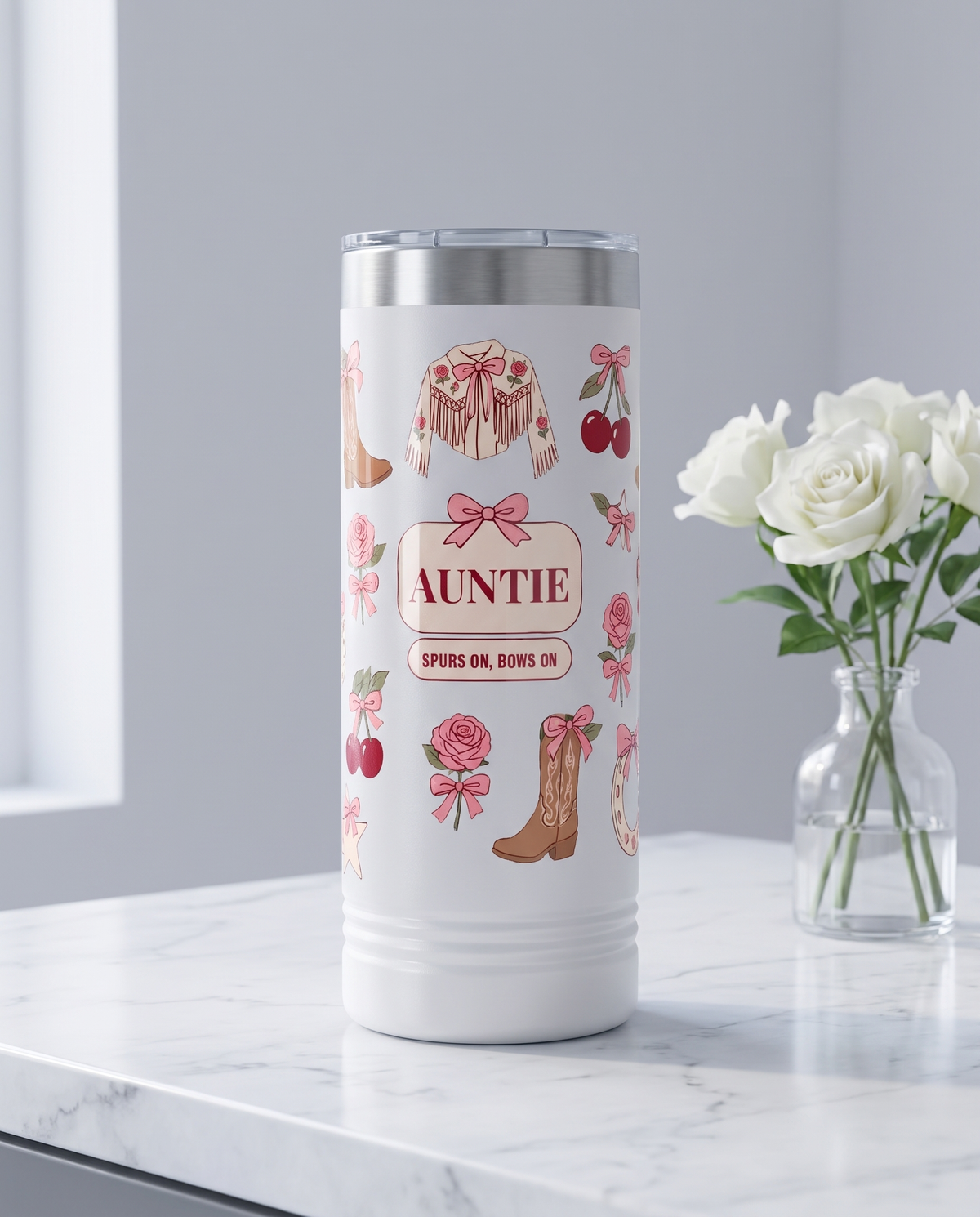 Coquette Cowgirl, Spurs On Bows On wrap on a white 22oz Skinny tumbler personalized AUNTIE, SPURS ON, BOWS ON, a white marble vanity top with a vase of white roses