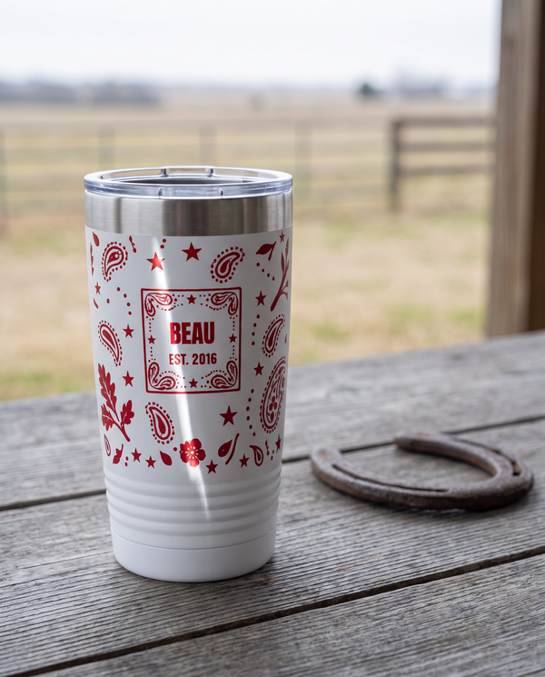 Bandana Paisley, Est. Year wrap on a white 20oz tumbler personalized BEAU, EST. 2016, a weathered barnwood table on a ranch porch