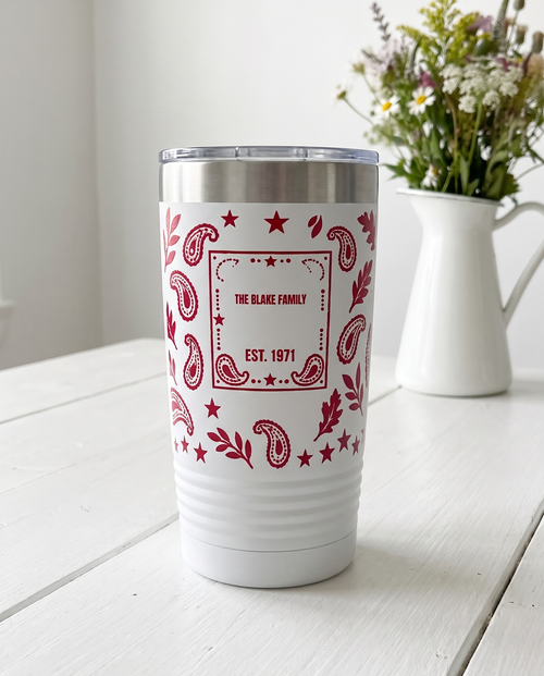 Bandana Paisley, Family Name wrap on a white 20oz tumbler personalized THE BLAKE FAMILY, EST. 1971, three-quarter view showing the ribbed lower wall, a white-painted farmhouse kitchen counter