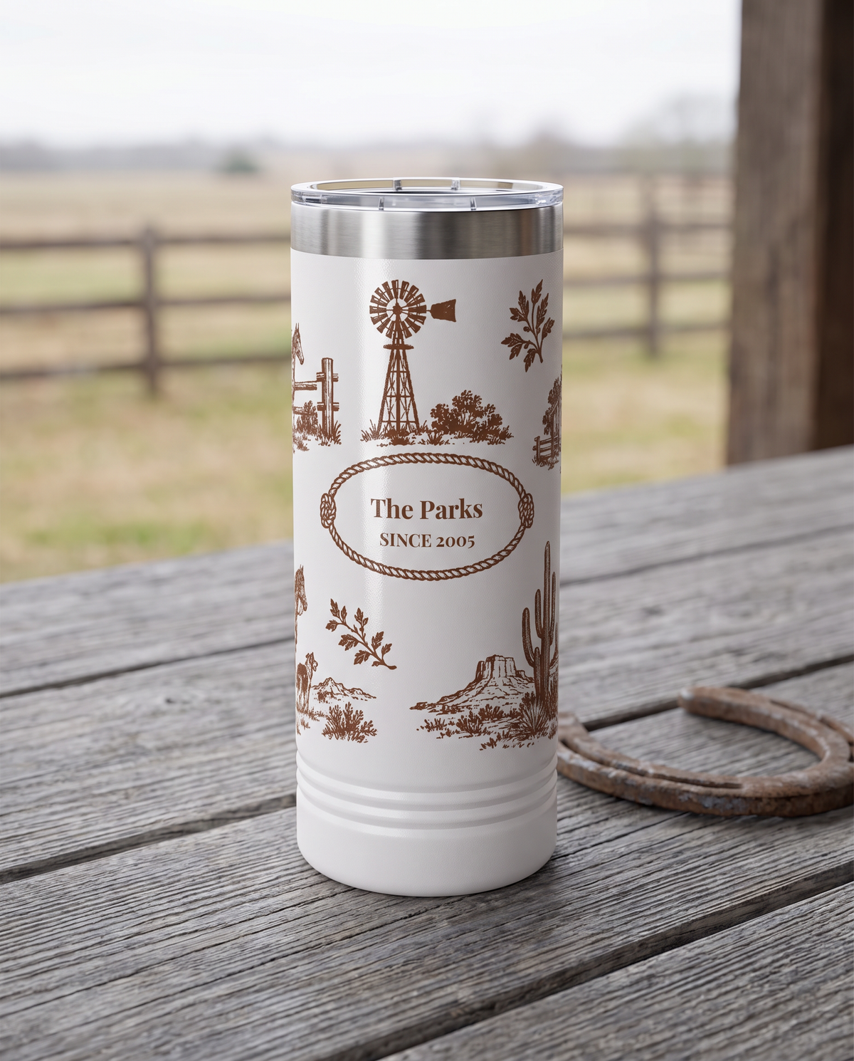 Western Toile, Windmill and Barn wrap on a white 22oz Skinny tumbler personalized THE PARKS, SINCE 2005, a weathered barnwood table on a ranch porch