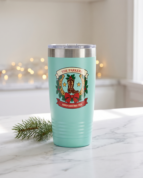 Cowboy Christmas, Horseshoe Wreath badge on a teal 20oz tumbler personalized THE PARKERS, RANCH CHRISTMAS 2026, a white marble kitchen counter with a sprig of pine
