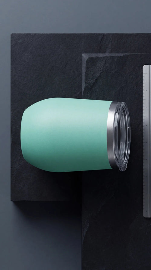 Hand-held Teal 12oz Wine Tumbler in a Pomelli setting - Industrial Grade Branding