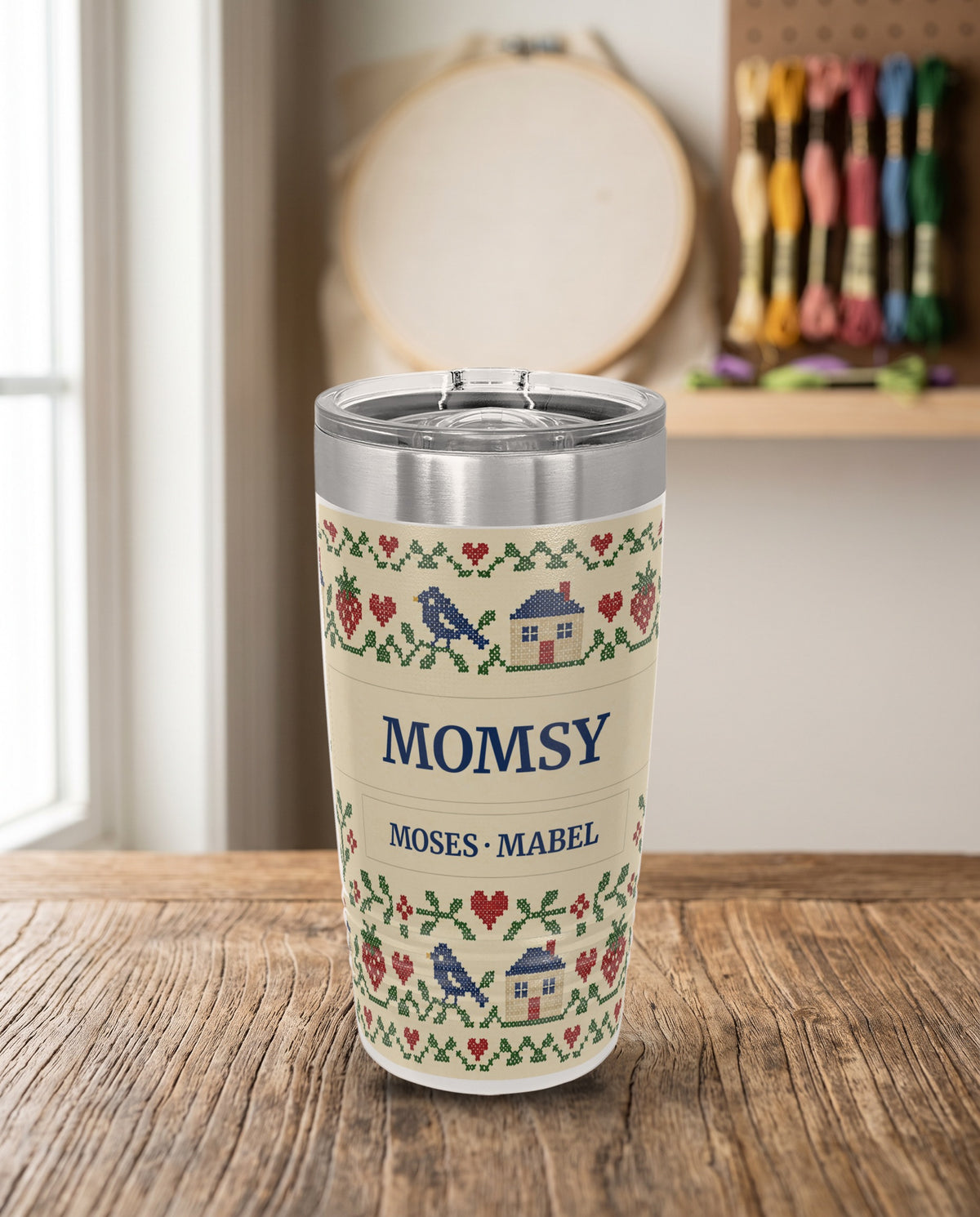 Cross-Stitch Sampler, a cross-stitch sampler in red, green, navy and cream, printed all the way around a 20oz Ringneck tumbler in White, sample name MOMSY