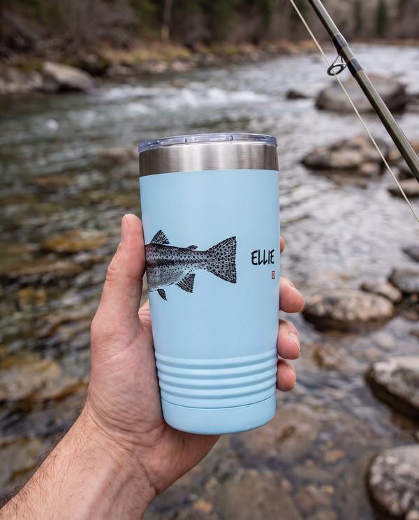 Gyotaku Rainbow Trout personalized fishing tumbler held beside a mountain river, name ELLIE