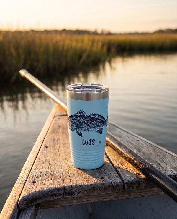 Gyotaku Redfish personalized fishing tumbler in light blue on the bow of a boat in a coastal marsh at golden hour, name LUIS
