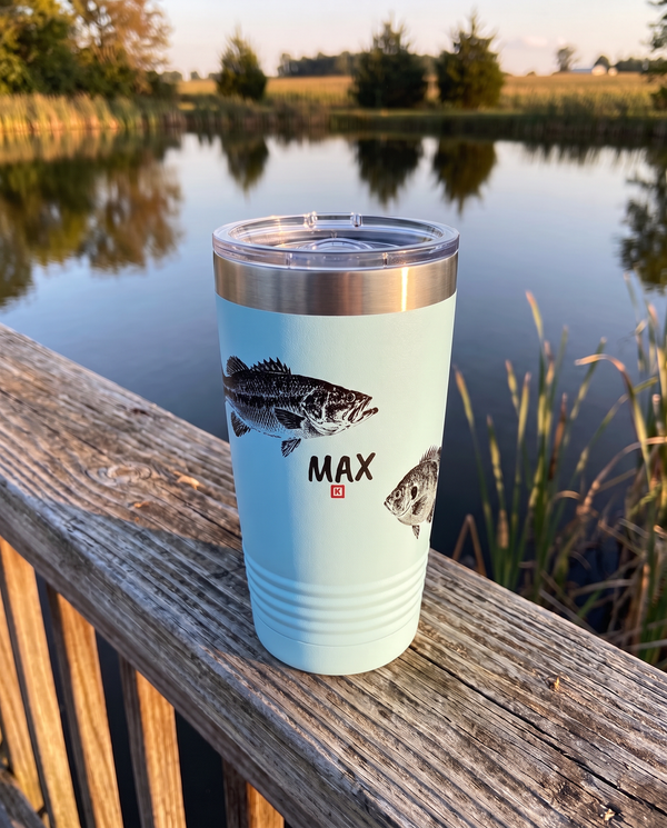 Gyotaku Bass and Bluegill personalized fishing tumbler in light blue on a pier railing over a calm pond, name MAX
