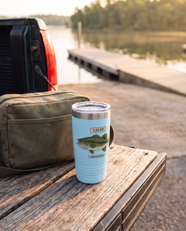 Field Guide Largemouth Bass personalized tumbler in light blue on a pickup tailgate by a lake boat ramp, name CALEB