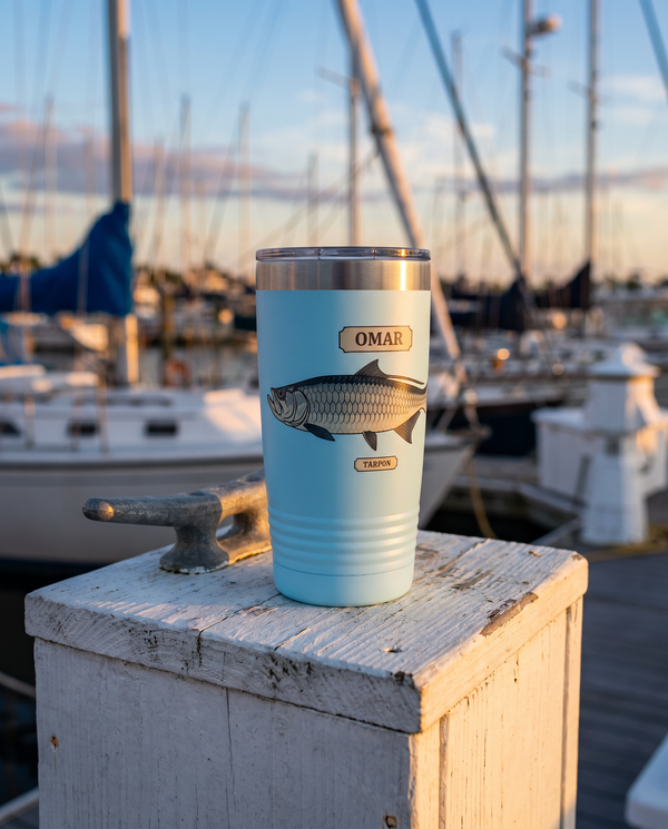 Field Guide Tarpon personalized tumbler in light blue on a marina dock at sunset, name OMAR