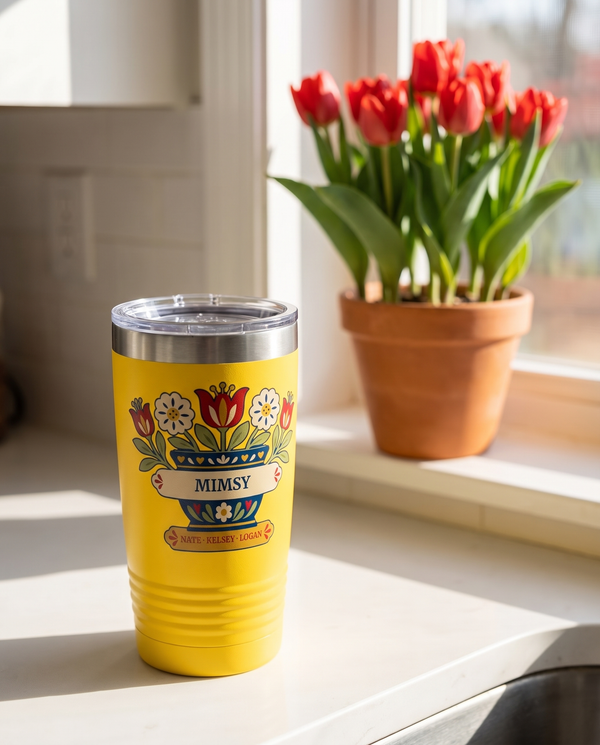 Tulip Pot, a folk flower pot in navy, red, cream, gold and sage, UV printed on the front of a 20oz Ringneck tumbler in Yellow, sample name MIMSY, sits on a sunny white kitchen counter by a window, potted red tulips on the sill far behind