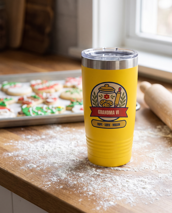 Cookie Jar Badge, a cookie jar badge in cream, gold, red, navy and olive, UV printed on the front of a 20oz Ringneck tumbler in Yellow, sample name GRANDMA VI, sits on a kitchen counter dusted with flour, a tray of decorated Christmas cookies and a rolling pin far behind