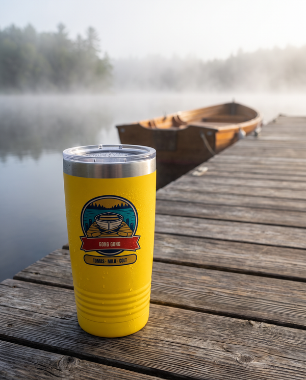 Rowboat Dock Badge, a lake dock badge in teal, gold, cream, red and navy, UV printed on the front of a 20oz Ringneck tumbler in Yellow, sample name GONG GONG, sits on the weathered boards of a lake dock in morning mist, a wooden rowboat far behind