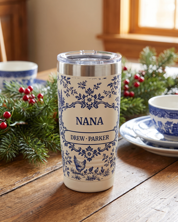 Blue Toile, a navy toile country scene on cream, printed all the way around a 20oz Ringneck tumbler in White, sample name NANA, sits on a breakfast table at Christmas with blue and white china and fresh greenery far behind