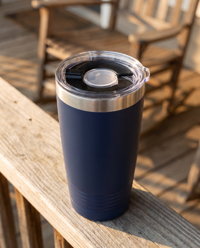 Magnetic slider lid on a navy 20oz Ringneck tumbler, on a porch rail in evening sun