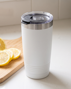 Snap-shut lid with its black flip cover closed on a white 20oz Ringneck tumbler, kitchen counter with sliced lemons