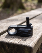 Black flip-top bottle lid on its own with carry loop and straw spout, on a wooden bench