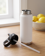 Replacement straw fitted under a flip-top lid beside an open white 20oz water bottle, on a kitchen counter