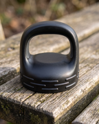Black lug lid on its own with ribbed grip and tall carry loop, on a weathered wooden bench