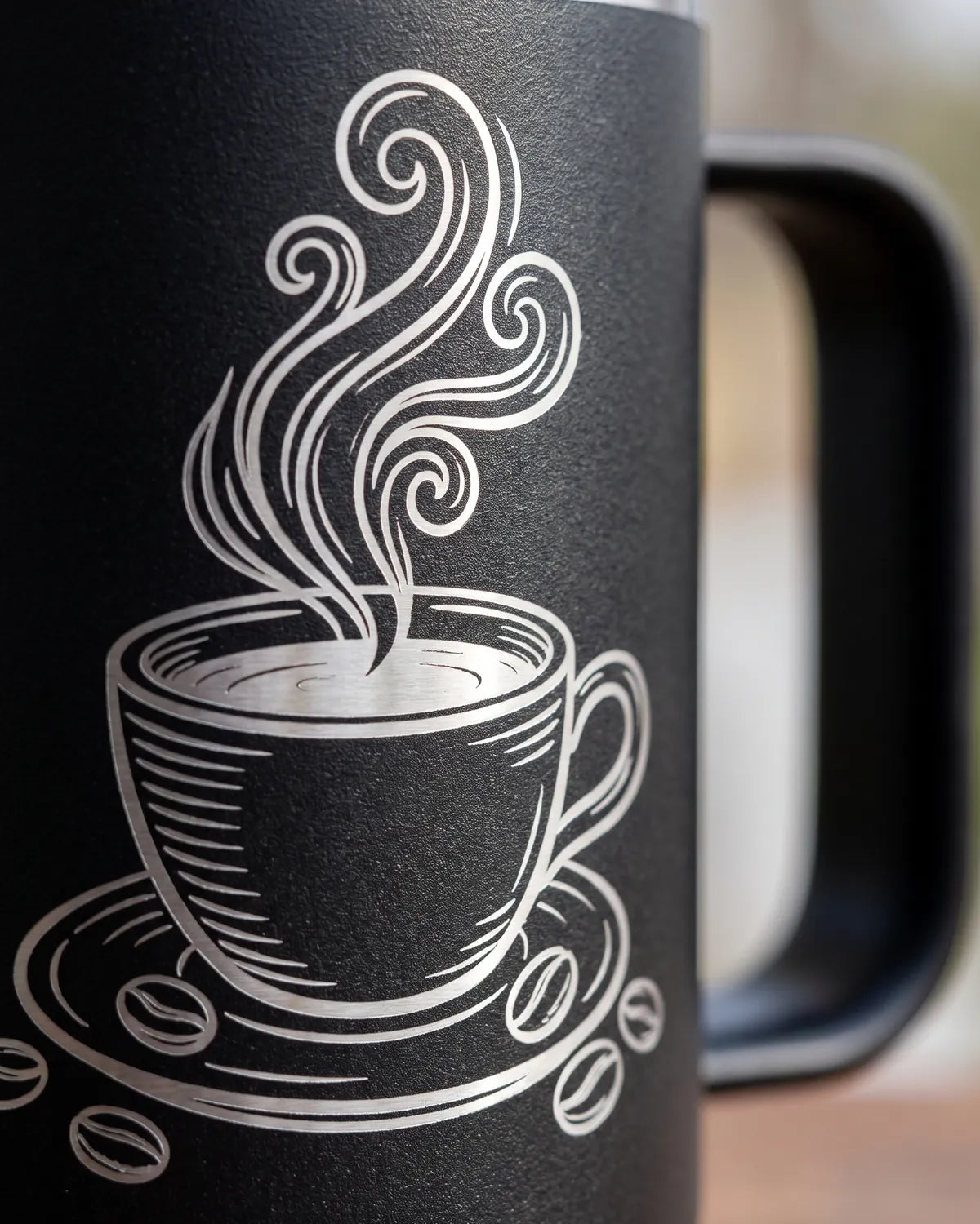 Engraved coffee cup line art on a black stainless mug